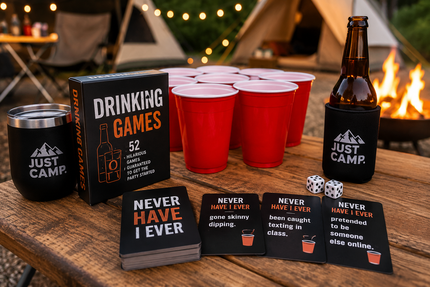 Camping drinking games setup with cards, cups and drinks on a campsite table beside a campfire and tents.